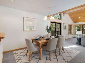 Experience cozy dining in this charming space, featuring a rustic wooden table set for six and comfortable upholstered chairs.