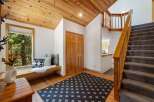 Step into this inviting entryway featuring a cozy window seat perfect for enjoying the scenic forest views.