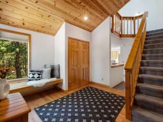 Step into this inviting entryway featuring a cozy window seat perfect for enjoying the scenic forest views.