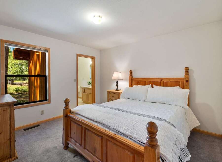 This charming bedroom features a cozy wooden bed with crisp white linens, perfect for a restful night's sleep.