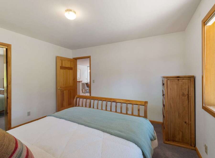 This cozy bedroom features a comfortable bed with a light blue throw, perfect for relaxing.