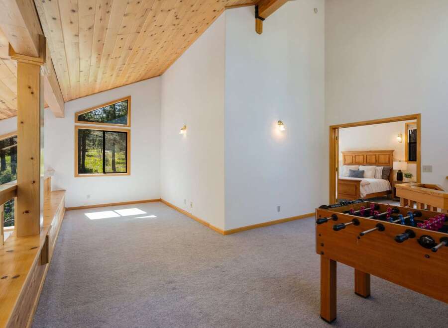 Experience the perfect blend of relaxation and recreation in this spacious loft area, featuring a fun foosball table and a cozy seating nook overlooking the surrounding forest.