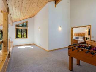 Experience the perfect blend of relaxation and recreation in this spacious loft area, featuring a fun foosball table and a cozy seating nook overlooking the surrounding forest.