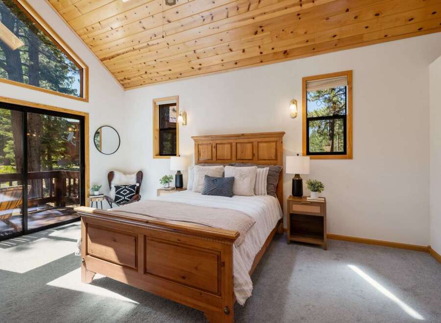 Experience rustic charm in this cozy bedroom featuring a beautiful wooden bed frame and vaulted wood-paneled ceilings.
