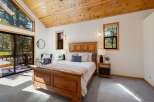 Experience rustic charm in this cozy bedroom featuring a beautiful wooden bed frame and vaulted wood-paneled ceilings.
