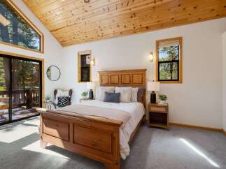 Experience rustic charm in this cozy bedroom featuring a beautiful wooden bed frame and vaulted wood-paneled ceilings.