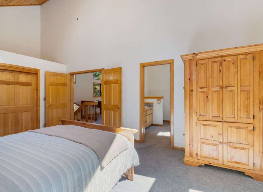 Discover this charming bedroom featuring a spacious wooden armoire and a comfortable bed.