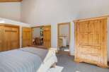 Discover this charming bedroom featuring a spacious wooden armoire and a comfortable bed.