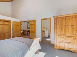 Discover this charming bedroom featuring a spacious wooden armoire and a comfortable bed.
