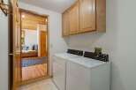 This laundry room features a white top-load washer and dryer set, complemented by light wood cabinetry above for ample storage.