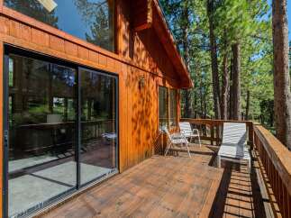 Enjoy the serene mountain lifestyle from this charming wooden cabin featuring a spacious deck perfect for outdoor relaxation.