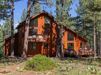 Nestled amidst tall pine trees, this stunning wooden A-frame home offers a serene retreat.