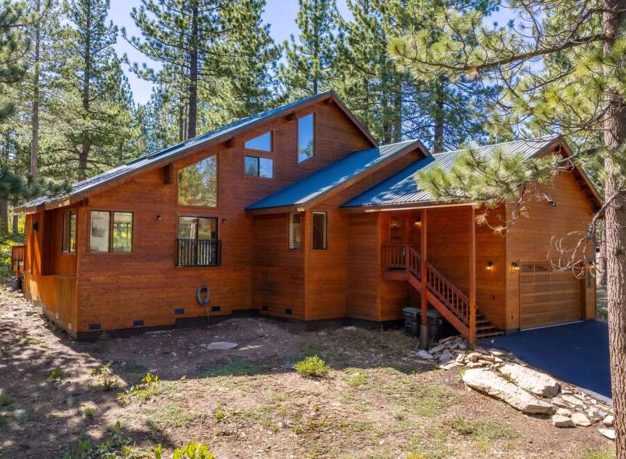 Nestled amongst tall pine trees, this stunning wooden home offers a rustic yet modern aesthetic.