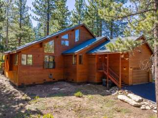 Nestled amongst tall pine trees, this stunning wooden home offers a rustic yet modern aesthetic.