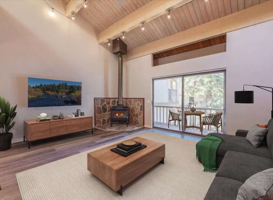 Experience cozy living in this stunning mountain retreat, featuring a striking stone-clad fireplace and a vaulted wood-beamed ceiling.