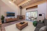 Experience cozy living in this stunning mountain retreat, featuring a striking stone-clad fireplace and a vaulted wood-beamed ceiling.