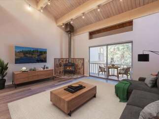 Experience cozy living in this stunning mountain retreat, featuring a striking stone-clad fireplace and a vaulted wood-beamed ceiling.