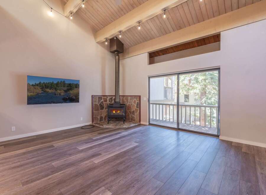 Experience the warmth of this inviting living space, featuring a striking stone-clad fireplace with a wood-burning stove as the centerpiece.