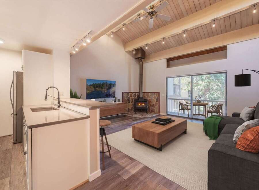 Experience modern living in this stunning open-concept space, featuring a sleek kitchen island and a cozy living area centered around a stone-clad fireplace.