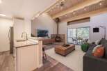 Experience modern living in this stunning open-concept space, featuring a sleek kitchen island and a cozy living area centered around a stone-clad fireplace.