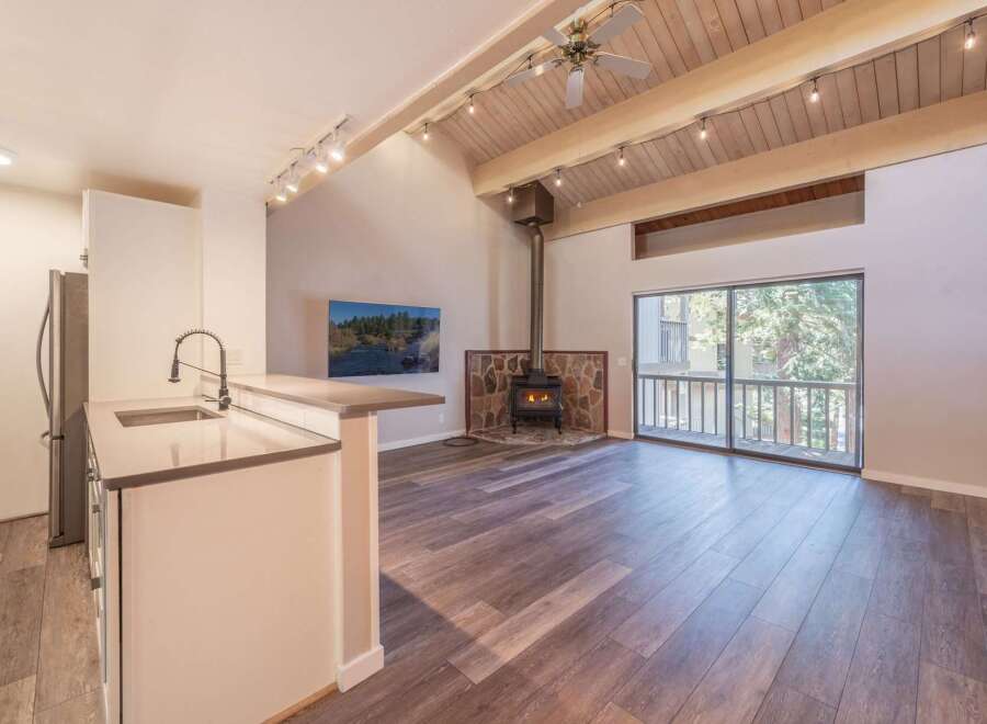Experience cozy living in this charming space featuring a rustic stone fireplace and a modern kitchen island with a sleek faucet.