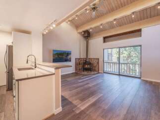 Experience cozy living in this charming space featuring a rustic stone fireplace and a modern kitchen island with a sleek faucet.
