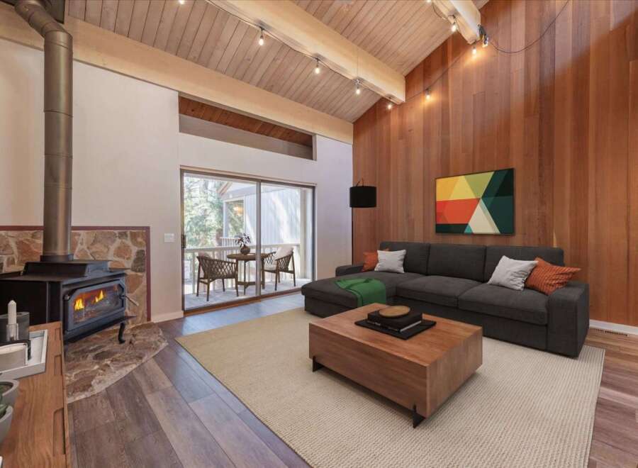 Experience cozy living in this stunning living room featuring a rustic stone fireplace with a wood-burning stove, perfect for chilly evenings.
