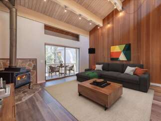 Experience cozy living in this stunning living room featuring a rustic stone fireplace with a wood-burning stove, perfect for chilly evenings.