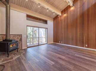 Experience cozy living in this spacious room featuring a striking stone fireplace with a wood-burning stove, perfect for chilly evenings.
