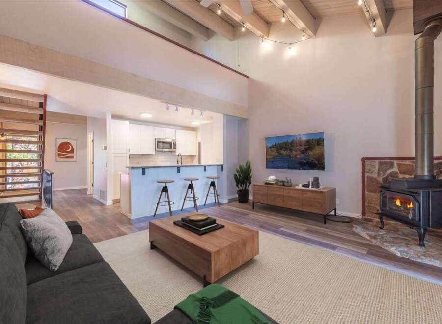 Experience modern living in this stunning open-concept space featuring a vaulted ceiling with exposed beams and a cozy fireplace.