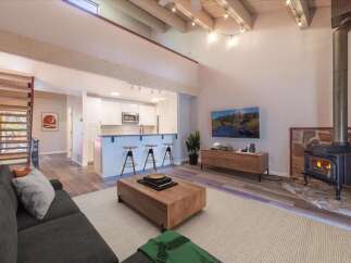 Experience modern living in this stunning open-concept space featuring a vaulted ceiling with exposed beams and a cozy fireplace.