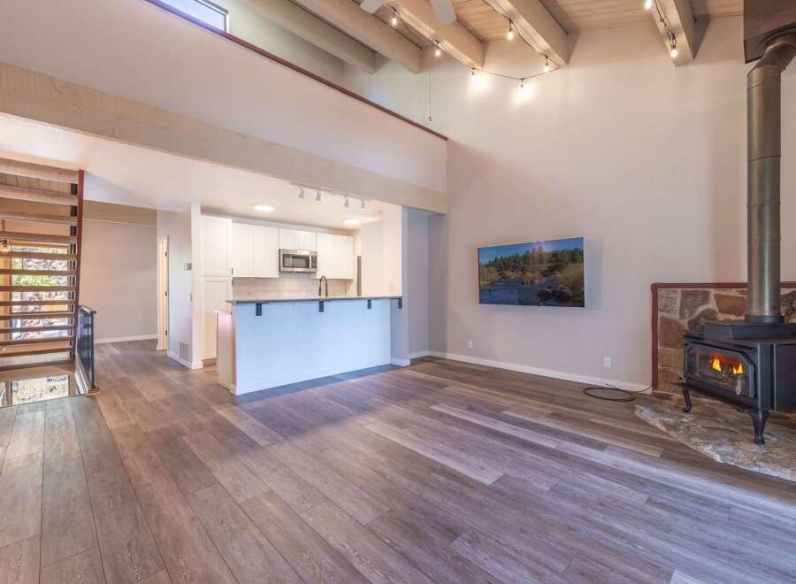 Experience modern living in this stunning open-concept space featuring a vaulted ceiling with exposed beams and a cozy wood-burning stove.