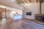 Experience modern living in this stunning open-concept space featuring a vaulted ceiling with exposed beams and a cozy wood-burning stove.