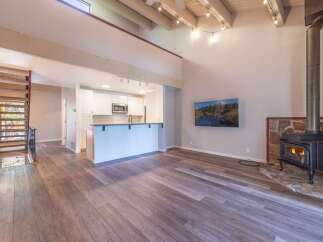 Experience modern living in this stunning open-concept space featuring a vaulted ceiling with exposed beams and a cozy wood-burning stove.