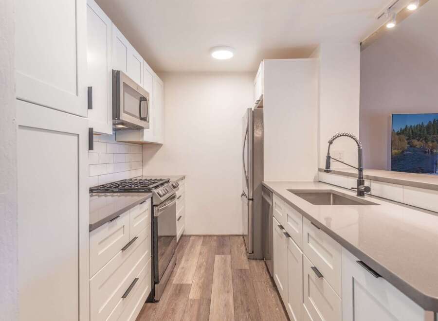 Discover this beautifully renovated kitchen, featuring sleek white cabinetry and modern stainless steel appliances, including a gas range and microwave.