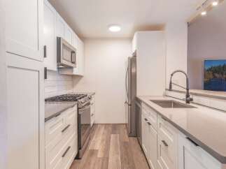 Discover this beautifully renovated kitchen, featuring sleek white cabinetry and modern stainless steel appliances, including a gas range and microwave.