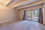 Step into this inviting room featuring a vaulted wood-beamed ceiling and plush carpeting, creating a warm and airy atmosphere.