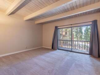 Step into this inviting room featuring a vaulted wood-beamed ceiling and plush carpeting, creating a warm and airy atmosphere.