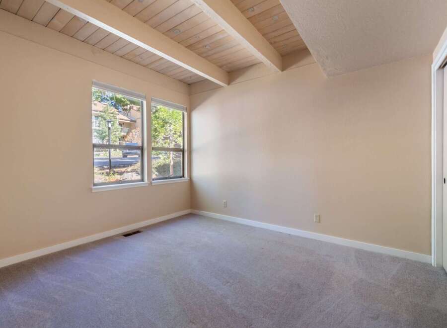 This spacious room features a vaulted ceiling with exposed wooden beams, adding a rustic charm and architectural interest.