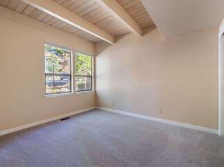This spacious room features a vaulted ceiling with exposed wooden beams, adding a rustic charm and architectural interest.