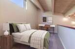 Discover this charming loft bedroom featuring a comfortable bed with plush pillows and a stylish green duvet.