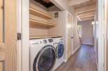 Discover the convenience of this home's dedicated laundry space, featuring a stacked washer and dryer set and ample overhead shelving for storage.