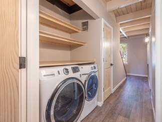Discover the convenience of this home's dedicated laundry space, featuring a stacked washer and dryer set and ample overhead shelving for storage.