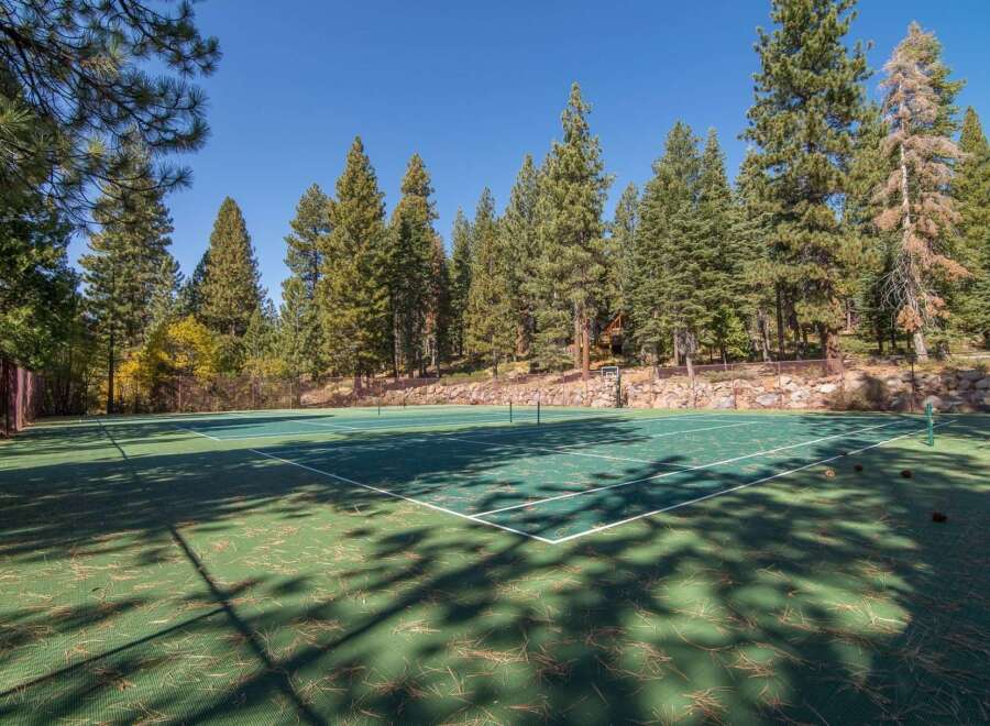 Enjoy outdoor recreation on this private tennis court, nestled amidst a serene forest setting.