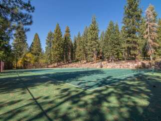 Enjoy outdoor recreation on this private tennis court, nestled amidst a serene forest setting.