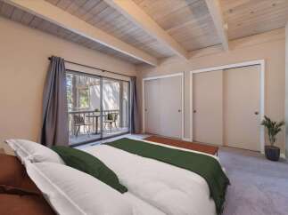 Step into this charming bedroom featuring a cozy bed with plush pillows and a stylish green throw.