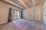 This spacious bedroom features a vaulted ceiling with exposed wooden beams, creating an airy and rustic ambiance.