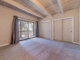This spacious bedroom features a vaulted ceiling with exposed wooden beams, creating an airy and rustic ambiance.