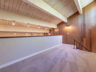Experience the unique charm of this loft space, featuring a vaulted wood-paneled ceiling with exposed beams and decorative string lights.