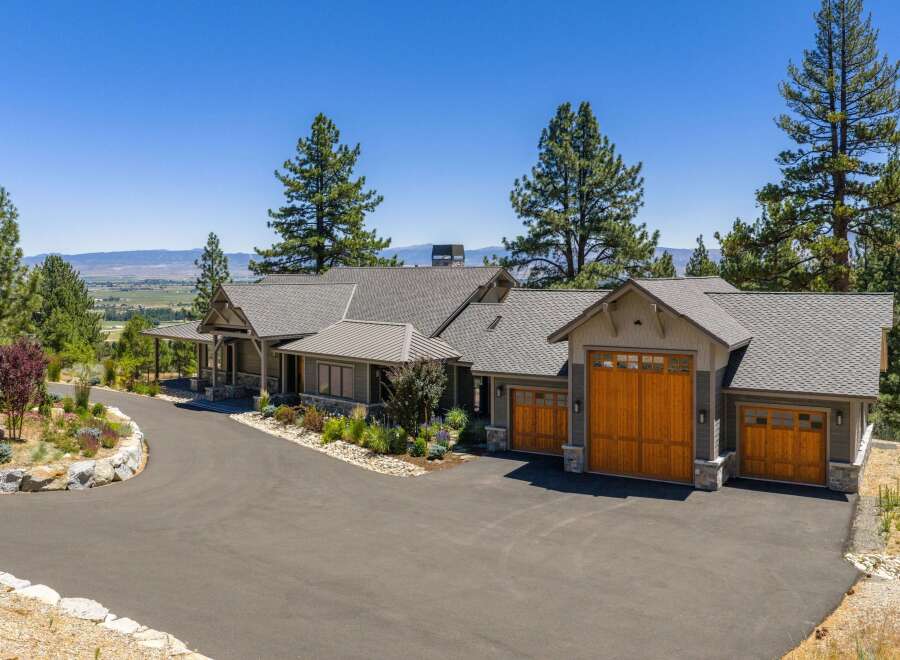 Experience luxury living in this stunning mountain home, featuring a grand entrance with a covered porch and stone accents.
